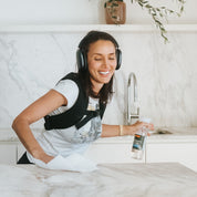 Woman wearing a weighted vest and headphones, cleaning kitchen.