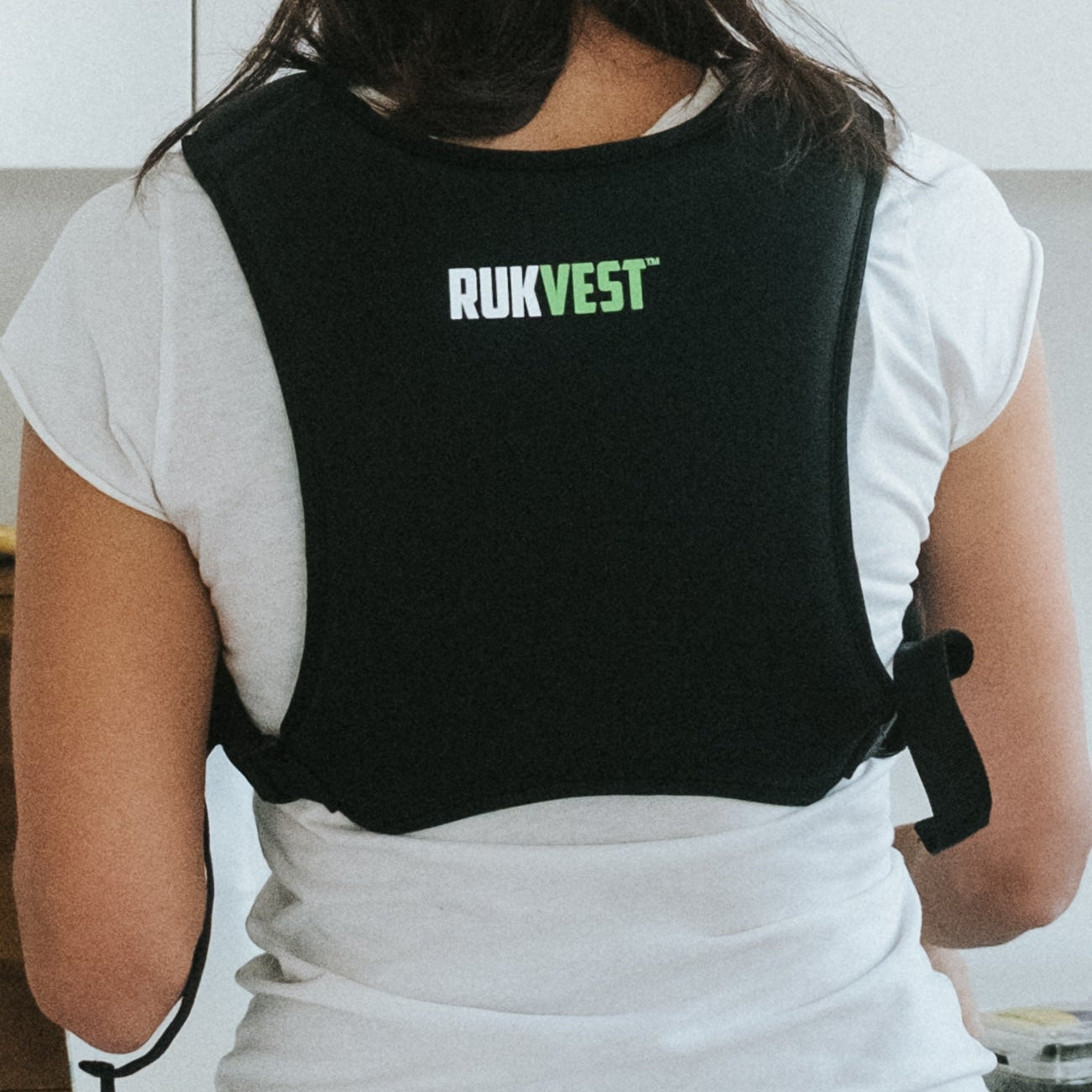 Person wearing a black RUKVEST vest in a kitchen setting